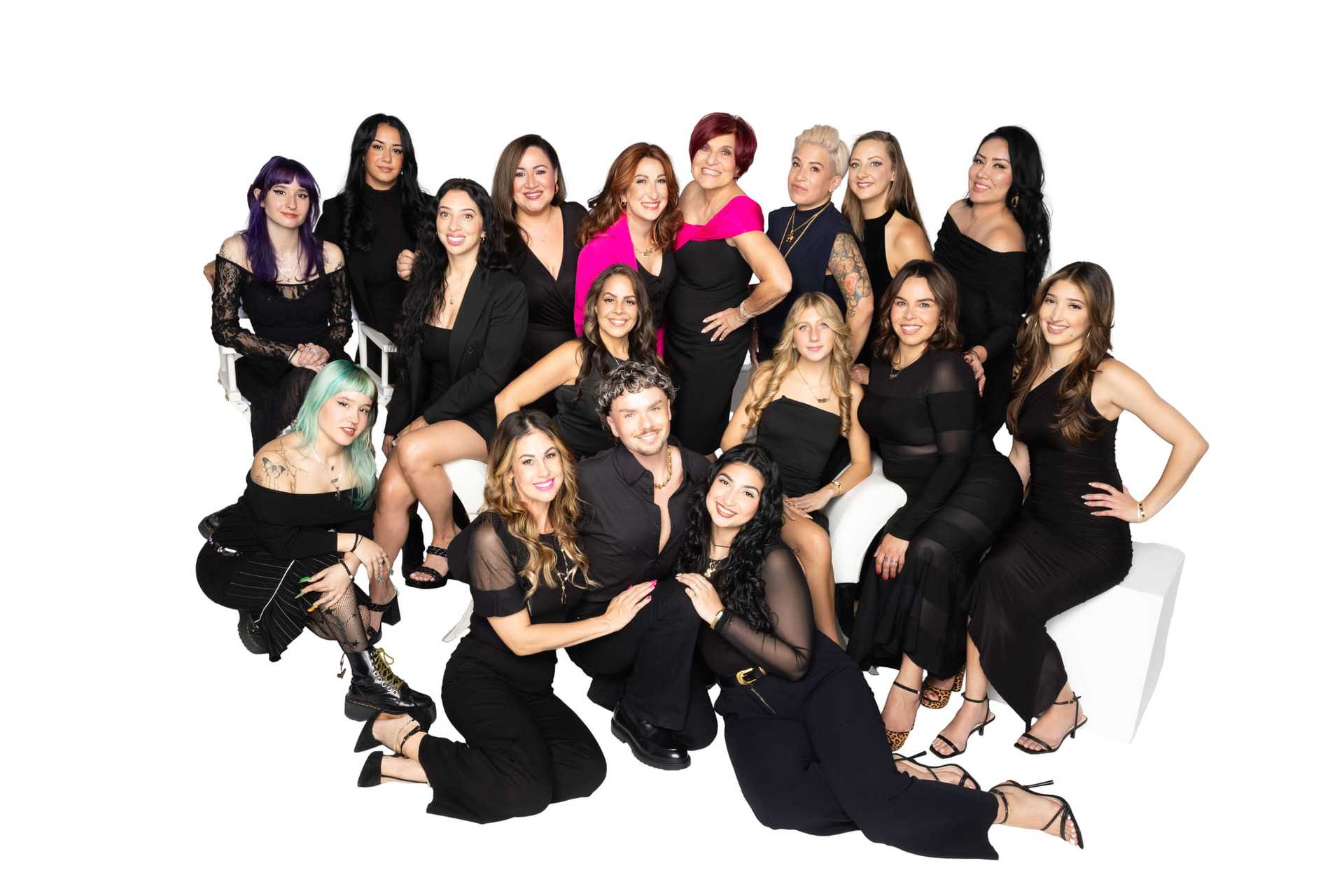 A group of 18 people posing together, all dressed in elegant black outfits.